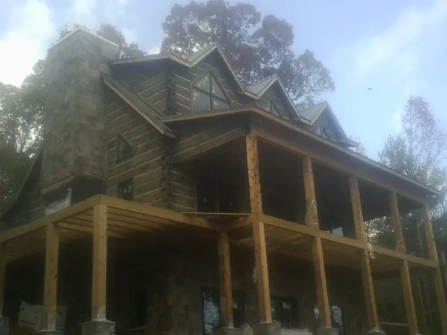 Stone chimney and dormers on a large log home with a timber porch in Petersburg